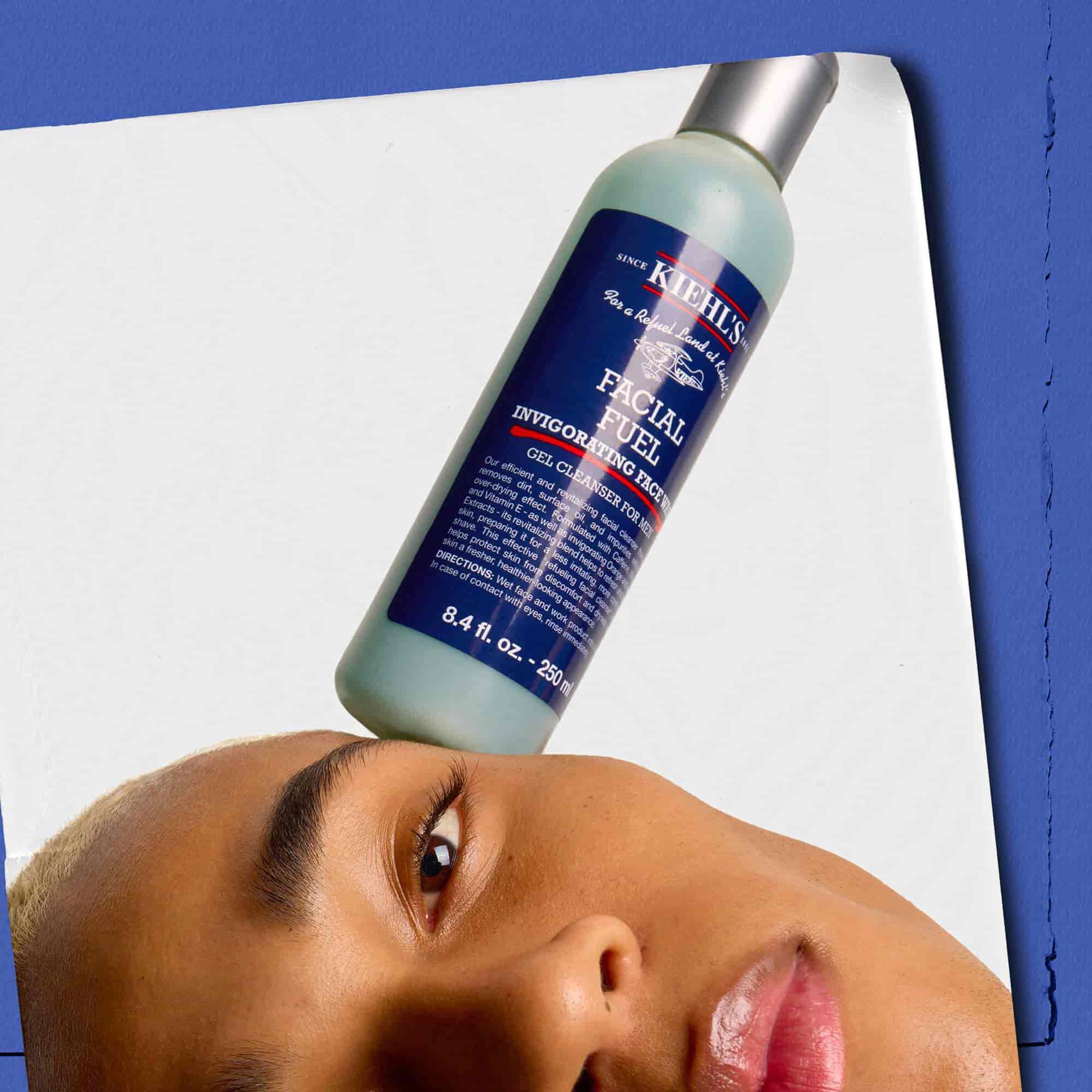 Model s bočicom energizirajućeg gela за pranje lica Kiehl's Facial Fuel na licu