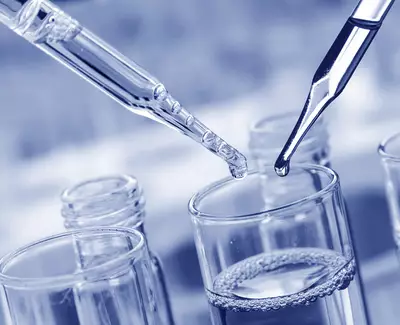 Close-up of two pipettes above a glass container filled with liquid, demonstrating a laboratory setting.