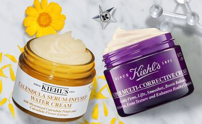 Alt text: Two skincare products from Kiehl's are displayed: a jar of Calendula Serum-Infused Water Cream and a jar of Super Multi-Corrective Cream, surrounded by yellow flower petals and a star emblem.