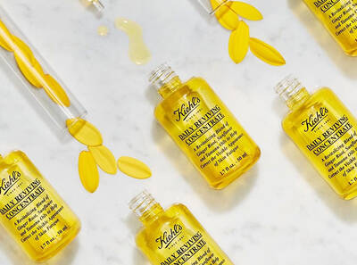 Šampioni Kiehl's Daily Reviving Concentrate u zlatnim bočicama na mramornoj površini s cvjetnim laticama.