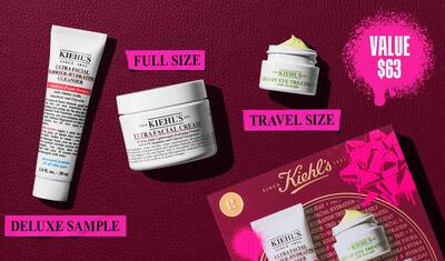 A graphic, set against a dark red textured background, features three and a gift box. A white tube of "KIEHL’S ULTRA FACIAL BARRIER-HYDRATING CLEANSER" is labeled "DELUXE SAMPLE" in bright pink. A white jar of "KIEHL’S ULTRA FACIAL CREAM" is labeled "FULL SIZE" in bright pink. A small white jar of "KIEHL’S CREAMY EYE TREATMENT WITH AVOCADO" with visible pale yellow cream is labeled "TRAVEL SIZE" in bright pink. In the lower right, a red Kiehl’s gift box showcasing the same three products is visible, decorated with bright pink graphic paint splatters and a bow design. In the upper right corner, a bright pink paint splatter contains the text "VALUE $63."