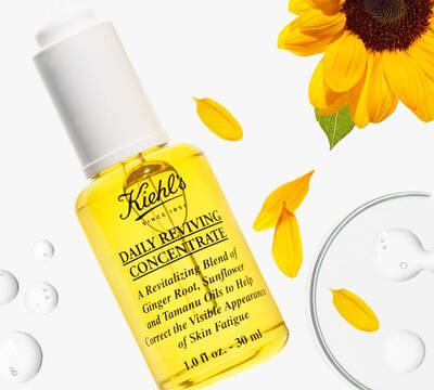 Bočica Kiehl's Daily Reviving Concentrate s uljima đumbira, suncokreta i tamanu, okružena cvjetovima suncokreta.