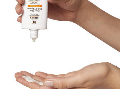 Ruke drže bočicu Kiehl's kreme dok se krema istiskuje na dlan.